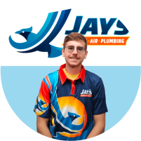 A man wearing glasses and a colorful branded work shirt with a plumbing company logo stands before a "Meet The Team" promotional background.