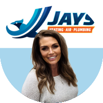 Meet the team: A woman with long brown hair and wearing a light-colored sweater stands in front of a logo for "Jays Heating - Air - Plumbing".